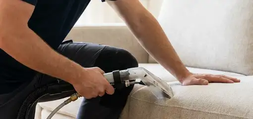 Professional upholstery cleaner deep-cleaning a fabric sofa with a handheld extraction tool, Albuquerque, NM.